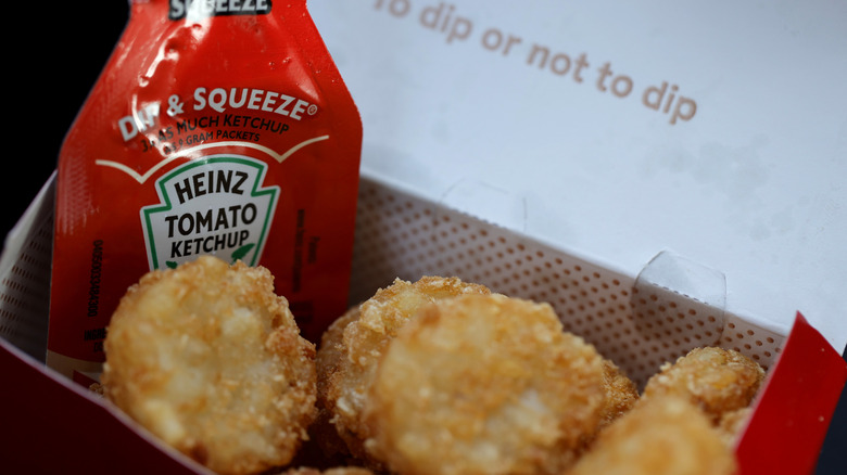Chick-fil-A Hash Browns sit in a box with a ketchup packet.
