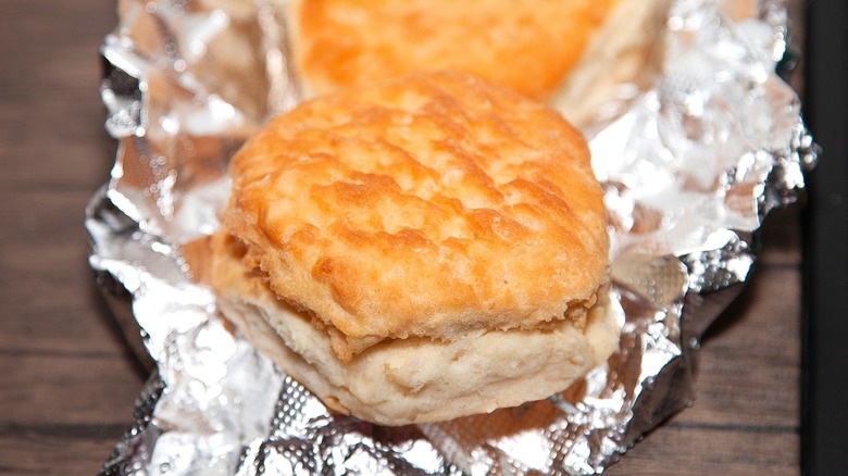 Buttery, golden biscuits on top of a crumpled piece of aluminum foil
