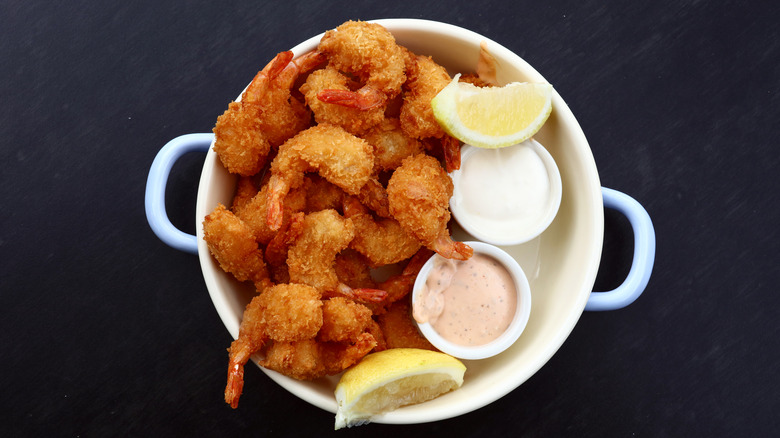 bowl of fried shrimp with dips and lemon wedges