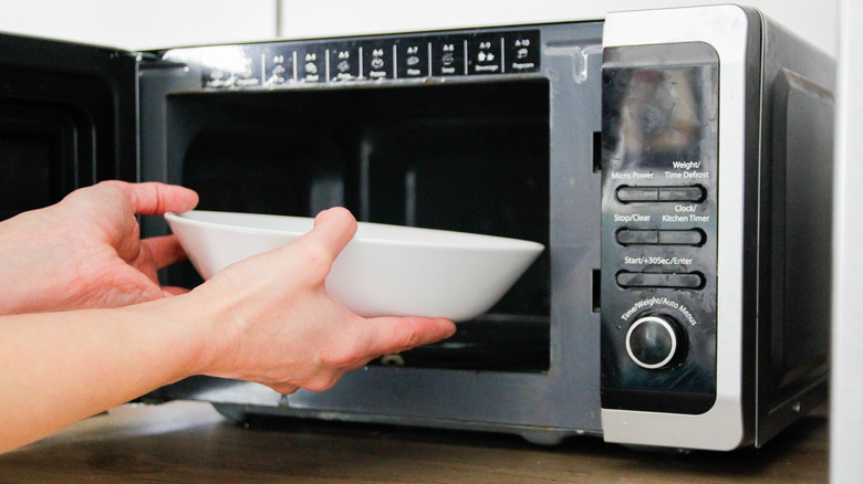 A bowl being placed into a microwave.