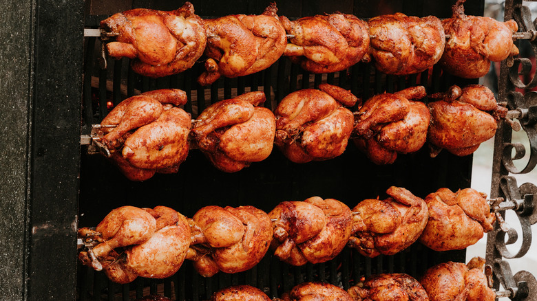 Rows of rotisserie chickens being cooked