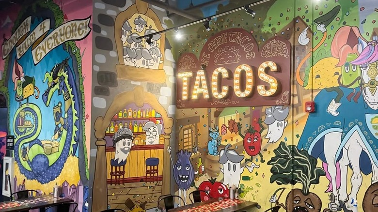 Condado Tacos' colorful interior, designed with quirky murals, complete with an illuminated sign that says "tacos."