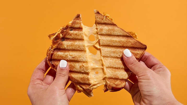 Woman pulling apart grilled cheese with cheese pull