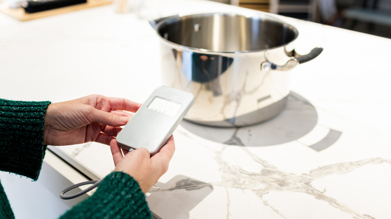Person using a pot on an invisible cooktop