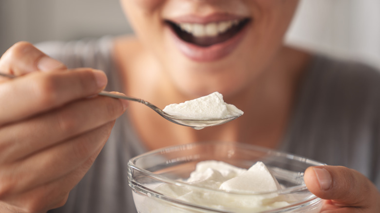Person bringing a spoonful of Greek yogurt to their mouth from a bowl