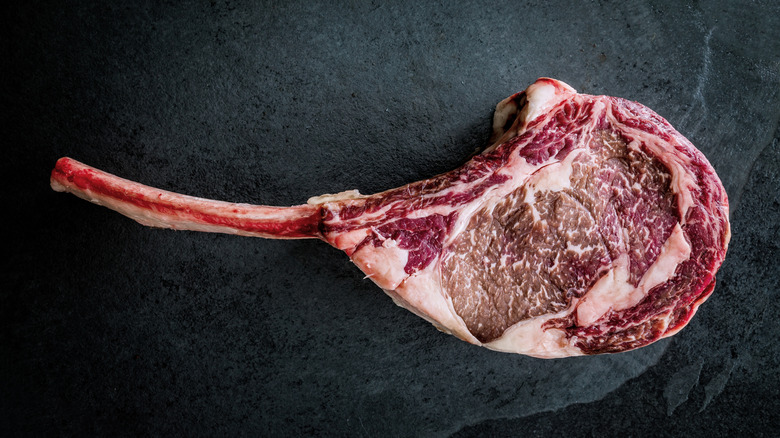 A single wagyu tomahawk steak on a black background