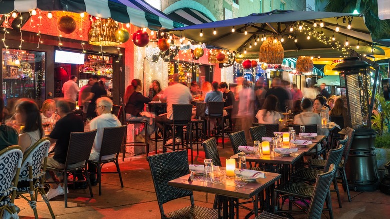 Outdoor dining locations with tables, chairs, and people eating