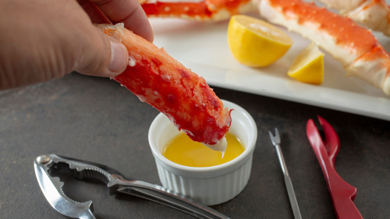 Person dipping crab leg into a ramekin of melted butter
