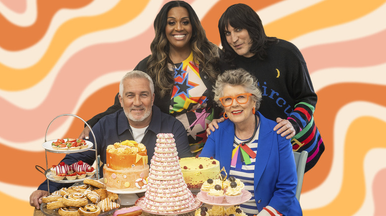 Presenters and judges of The Great British Baking Show behind a table of desserts