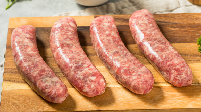 Raw sausages on a board.