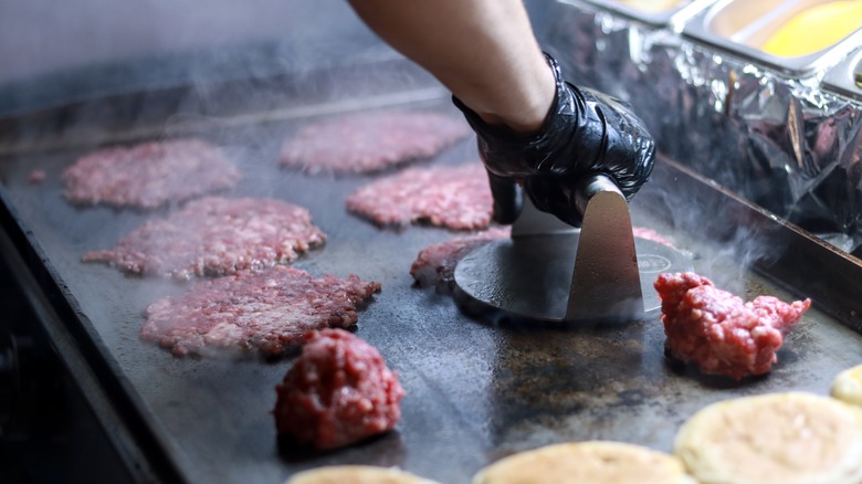 A cook making smash burgers