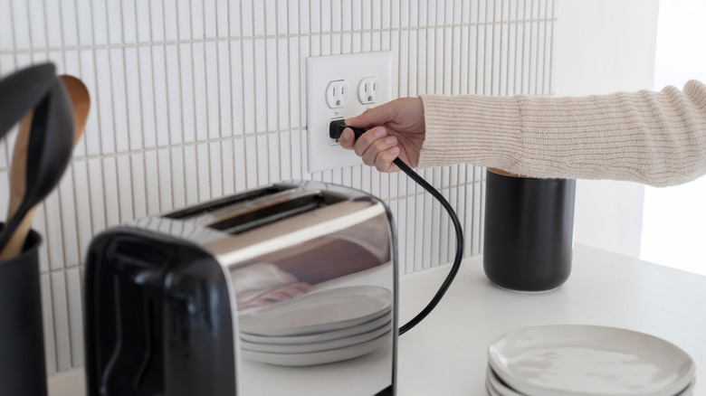 person plugging toaster into double outlet in a kitchen
