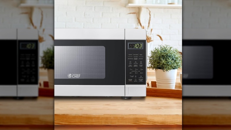 Commercial Chef microwave on a wooden surface next to a potted plant