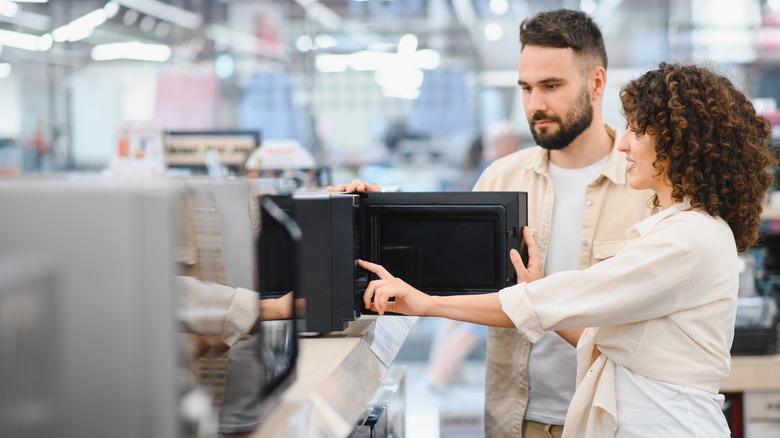 Couple in a store shopping for microwaves