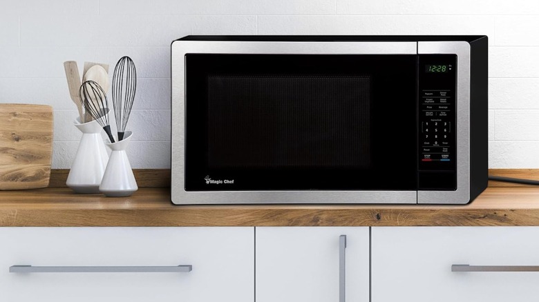 Magic Chef microwave sitting on counter top next to kitchen utensils