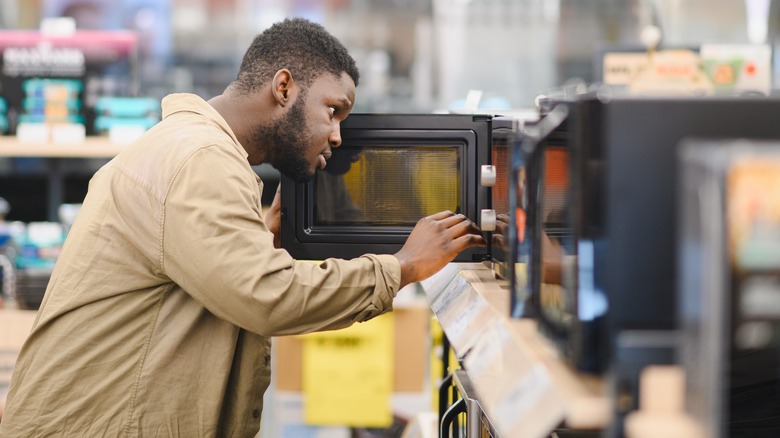 Man in a store looking inside a microwave