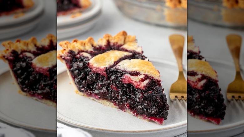 Slice of huckleberry pie on a white plate with a fork