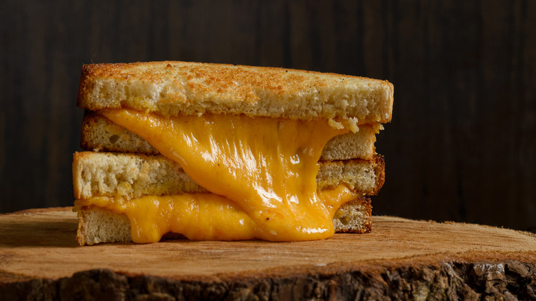 Two halves of a grilled cheese stacked on top of each other with cheese melting out