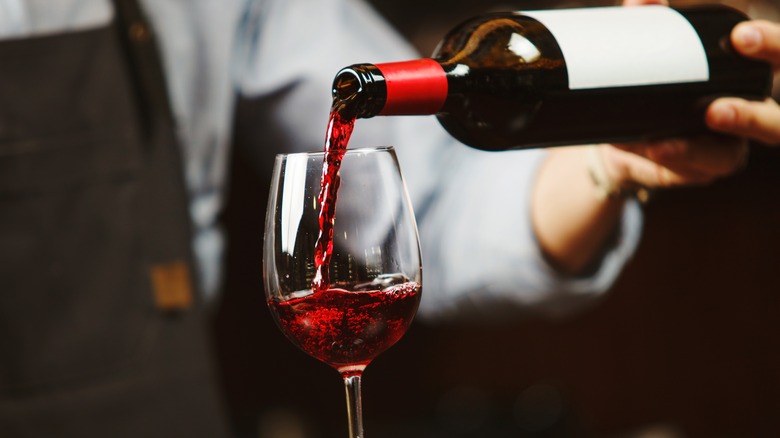 Waiter pouring red wine