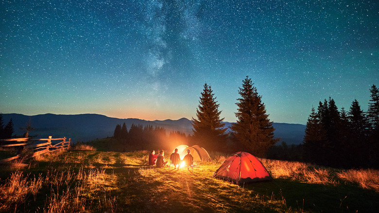 Camp site with people sitting around a fire at night