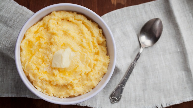 Cornmeal mush in white bowl with butter and spoon