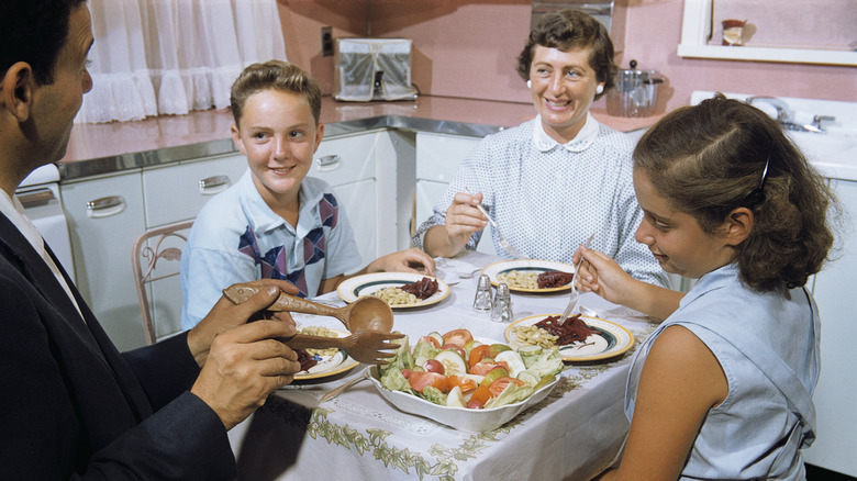 Vintage photo of father serving salad to his family