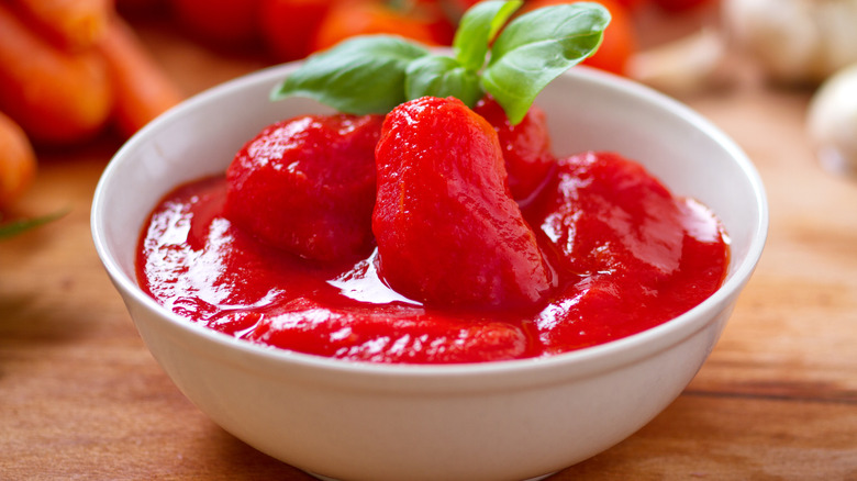 Peeled tomatoes and basil in ceramic bowl
