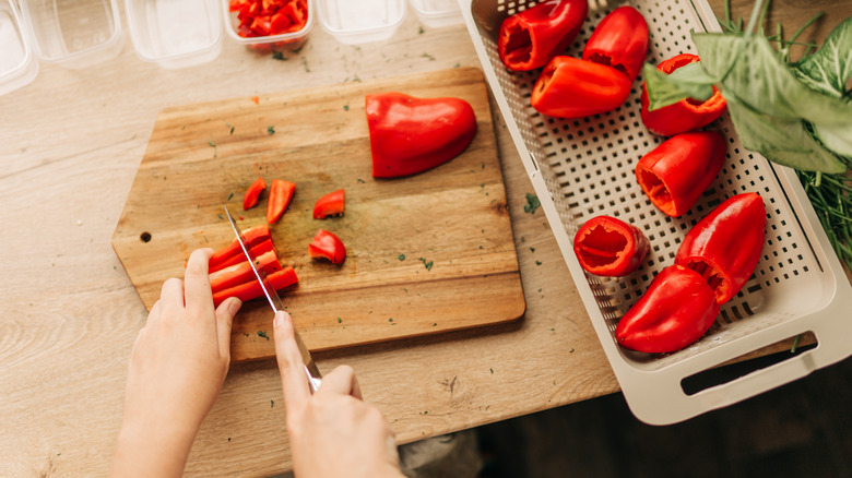hands cutting up washed red bell peppers