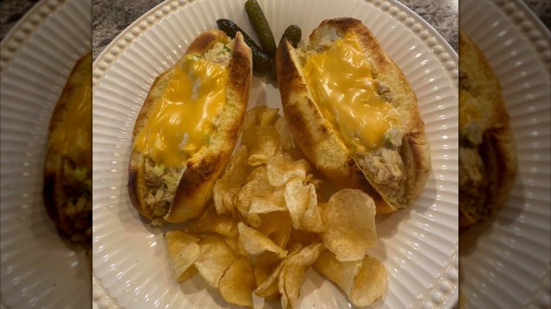 A tuna bumstead sandwich is served with chips and pickles