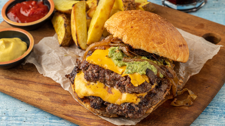 Smashburger with cheese on a wooden cutting board