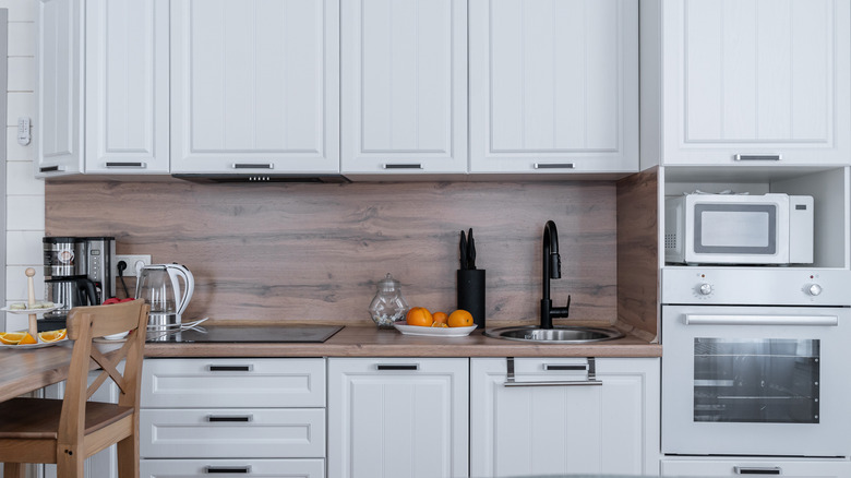 Grainy brown wood backsplash in mostly white kitchen