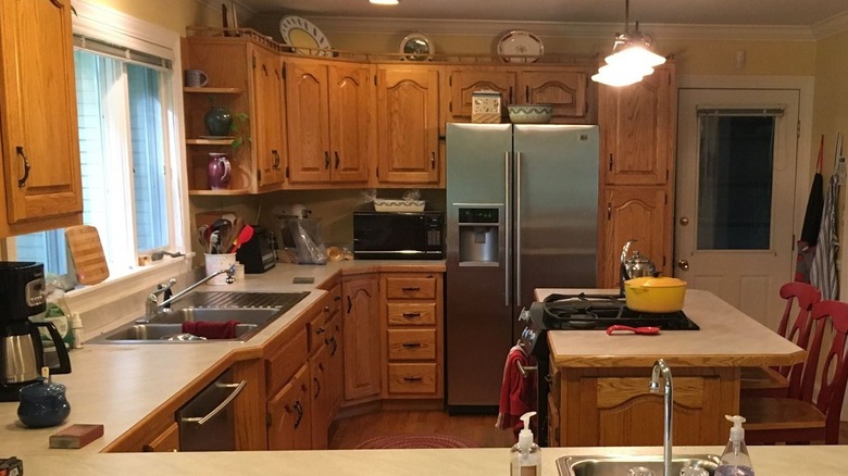 1990s style kitchen with light-colored wooden cabinets and decorative plates