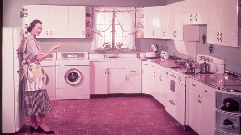 vintage photo of a 1950s kitchen with a smiling woman and appliances