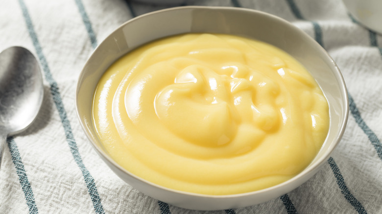 A white bowl of vanilla pudding on a cloth napkin.