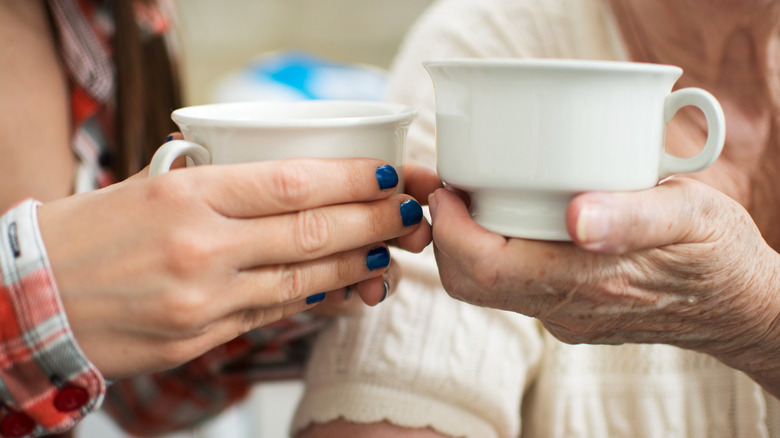 Young and old women holding cups.