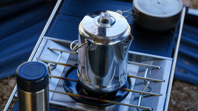 A coffee percolator on a campfire stove