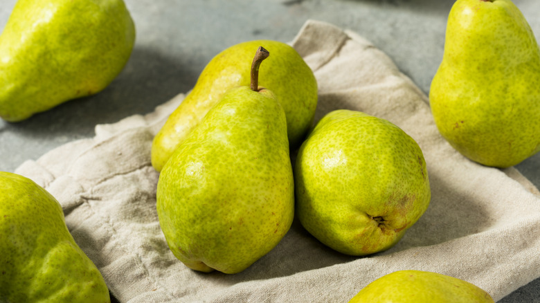Green pears are arranged on a cloth napkin.