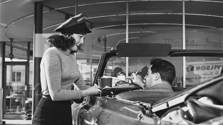 a waitress at a 1950s drive-in restaurant serving her customer