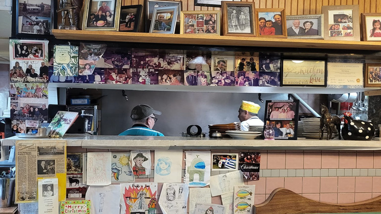 A view of the kitchen at Nick's Hi-Ho Cafe framed by photographs, drawings, and other memorabilia