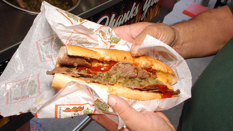 man holding sandwich from Geno's Steaks in hands