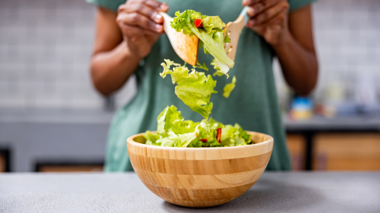 Someone mixing a green salad