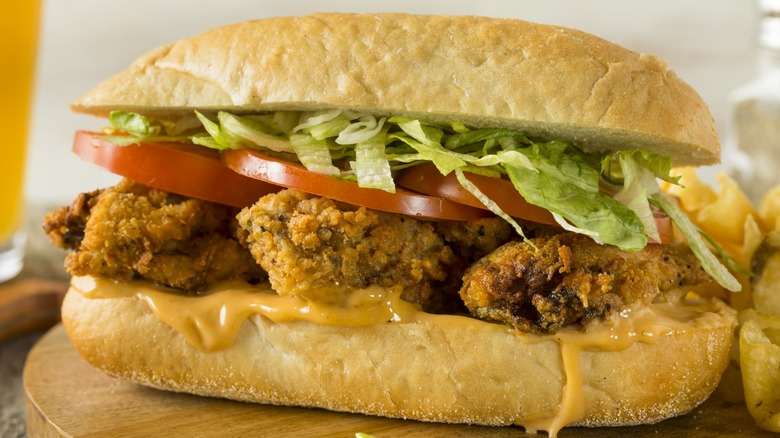 A fried oyster with lettuce and tomato po' boy sandwich.