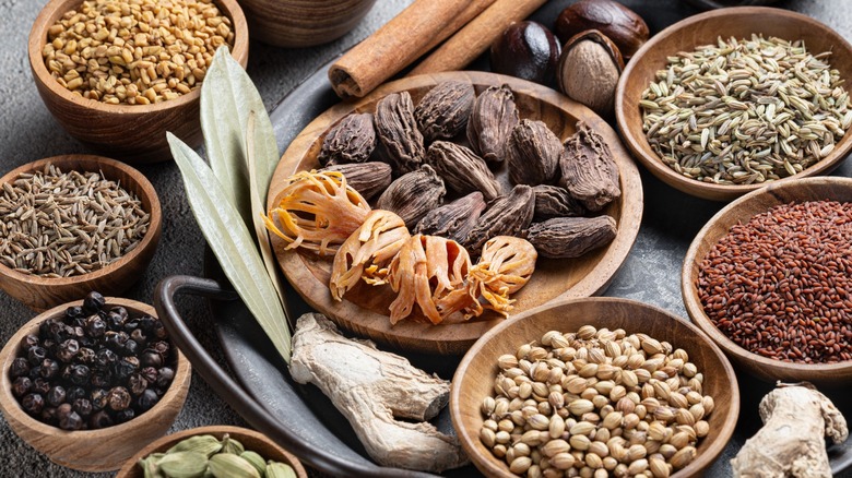 Small bowls of various whole spices  on a concrete table