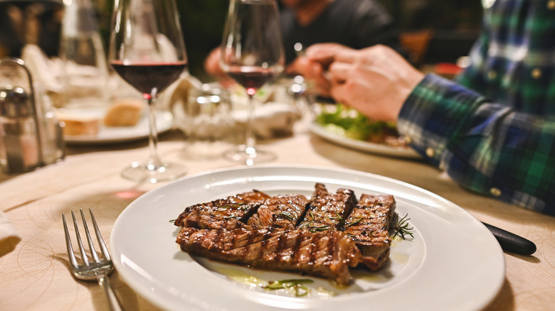 Grilled steak on a white plate at a restaurant.