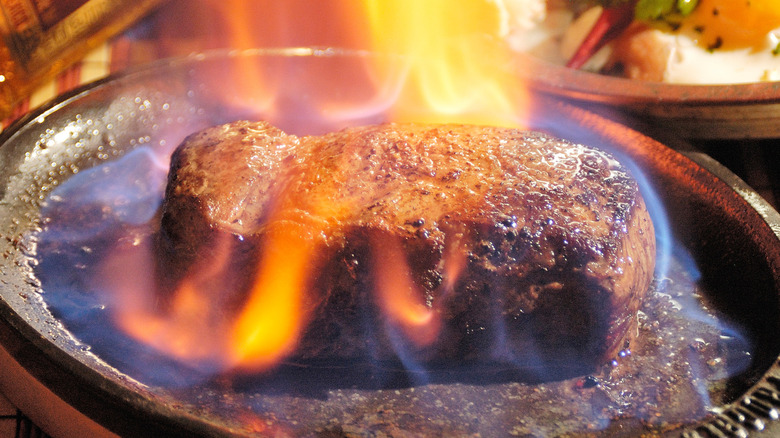 A steak being flambéed at the table.