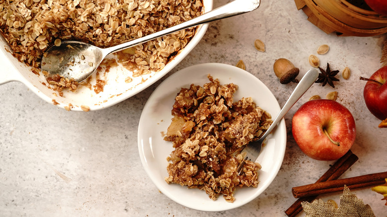 top down view of partially eaten bowl of apple crisp and tray of apple crisp