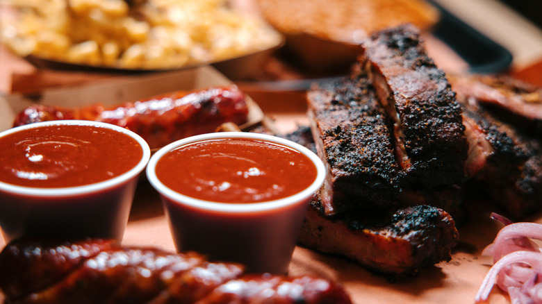 close up of barbecue sauce cups next to ribs