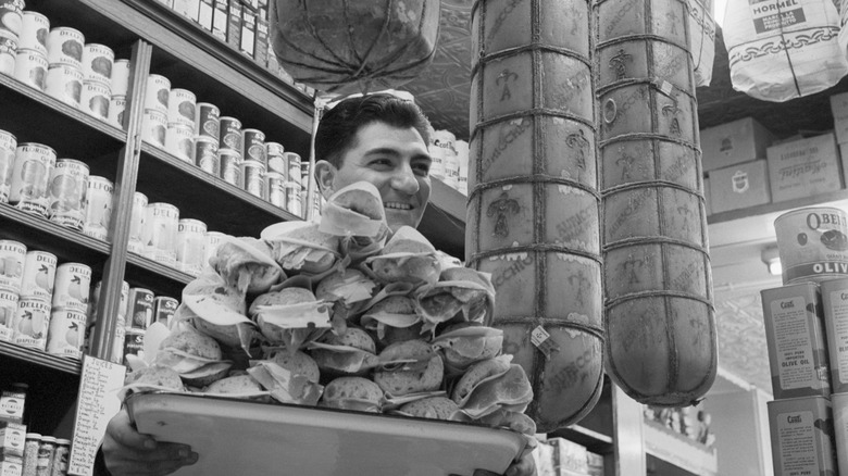 A vintage photo of a man holding a platter full of sandwiches