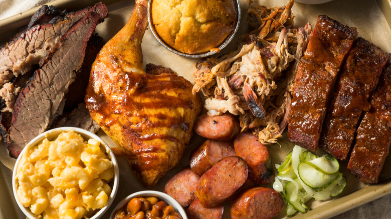 A barbecue platter featuring chicken, ribs, brisket, sausage, mac and cheese, and cornbread