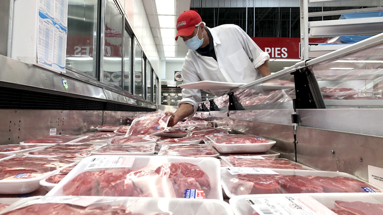 Costco employee restocking packages of steak